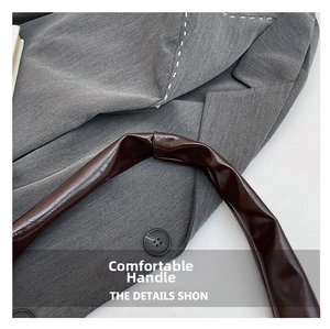 Detail shot of a dark brown glossy patent leather handle on a textured grey blazer
