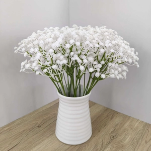 Close-up of white gypsophila artificial flowers in a striped ceramic vase on wood table
