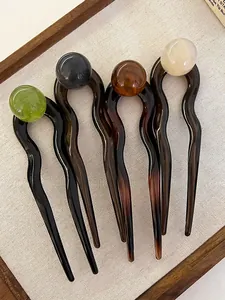 Gros plan de quatre épingles à cheveux en U avec perles colorées sur un plateau