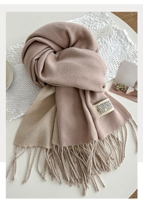 Detailed close-up of thick pink and beige scarf texture with long fringe and woven label