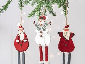 Detail of wooden Santa and Snowman ornaments with metal bells hanging on pine branches