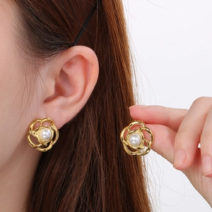 Macro detail of camellia flower earrings with pearl accent on gold titanium steel base
