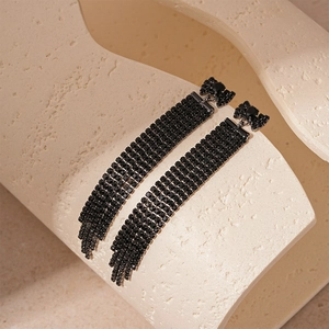 Détail macro des boucles d'oreilles nœud en strass noirs avec de longs pompons élégants