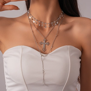 Detail of silver triple-layered necklace featuring crystal cross and star tassel pendants