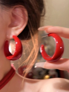 Close-up of red acrylic C-shaped hoop earrings worn to show fashion minimalist style
