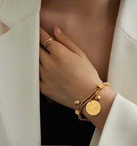 Détail du bracelet doré à double couche avec breloque ronde gravée Eternal Love