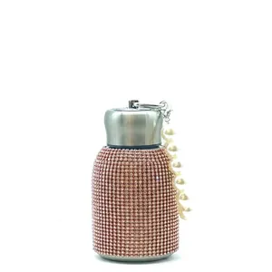 Macro detail of sparkly champagne pink rhinestone thermos with white pearl bead handle
