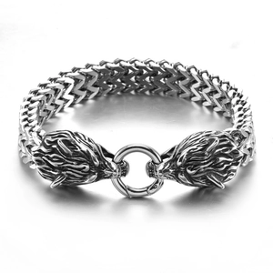 Detail of silver stainless steel viking bracelet featuring two wolf head charms and a clasp