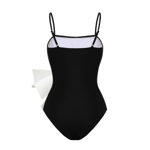 Rear view of one-piece swimsuit featuring a large white bow and adjustable straps