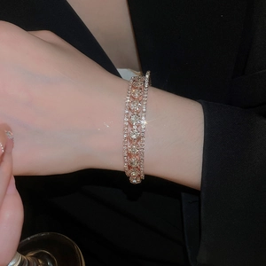 Macro detail of three-layer rose gold zircon bracelet shimmering on a black blazer sleeve