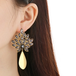 Vintage oversized gold leaf earrings with dark grey crystals on a female model