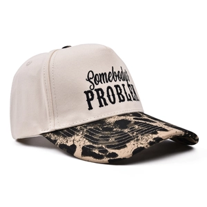 Close-up of Somebody's Problem embroidery on beige trucker hat with leopard print brim