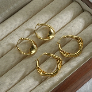 Polished and hammered gold stainless steel hoop earrings in a beige jewelry organizer