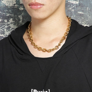 Dettaglio di una catena a maglie d'oro spessa da uomo in stile punk indossata dal modello