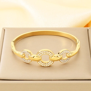 Detailed macro view of triple linked gold bangles with sparkling crystals on a display