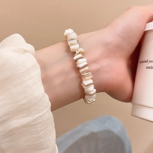 Detailed close-up of handmade irregular shell bead bracelet on model wrist