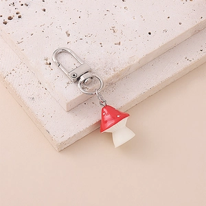 Close-up of a vibrant red mushroom keychain with durable metal clasp on a stone surface