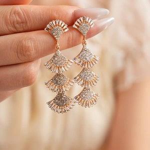 Macro shot of tiered fan-shaped fringe earrings with inlaid rhinestones and gold plating