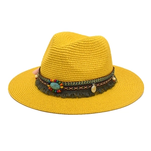 Detail of yellow straw jazz hat with woven band, blue turquoise and tassel accent
