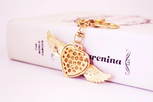 Close-up of golden heart with wings keychain featuring delicate embedded rhinestones