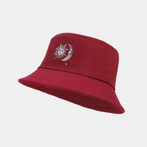 Close-up of embroidered sun and moon patterns on a deep burgundy cotton bucket hat