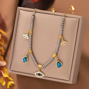 Detail of gold evil eye charms and blue teardrop pendants on grey beaded jewelry
