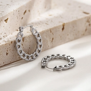 Detailed view of silver stainless steel chain-link hoop earrings on textured stone