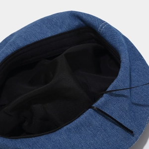 Detail view of denim beret hat showing black fabric lining and adjustable inner drawstring