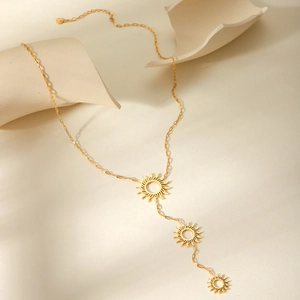 Detail of gold hollow sunburst charms on a stylish rectangular paperclip Y-chain necklace