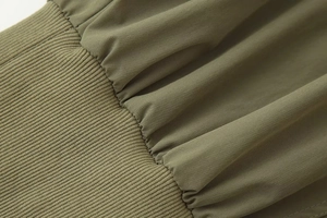 Détail d'une veste vert olive avec poignets en tricot côtelé et coutures plissées