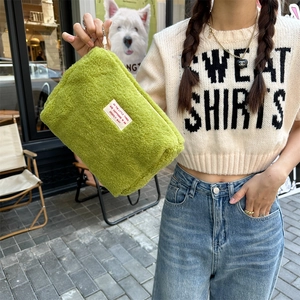 Detail of green sherpa storage bag with slogan patch and metal zipper closure