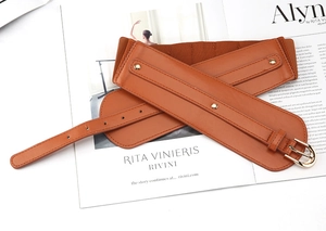 Detail of a brown wide elastic waist belt with PU leather front and gold buckle rivets