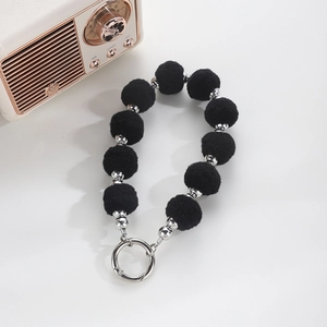 Detail of black pompom wristlet keychain with silver beads and metal buckle closure