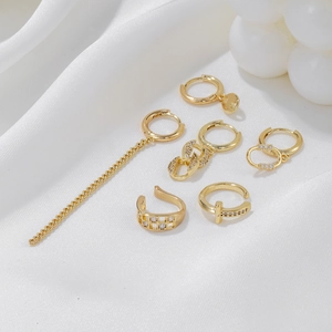 Golden chain link earrings set with cubic zirconia on white silk fabric background