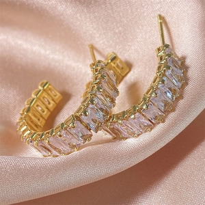 Détail de boucles d'oreilles créoles dorées serties de cristaux roses sur soie