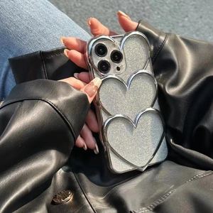 Detail of silver glitter iPhone case featuring three 3D metallic hearts on the back