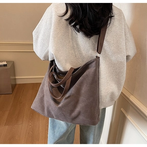 Detail of dark brown canvas tote bag showing side view with shoulder strap on a model