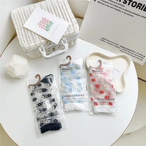Close-up of sheer mesh socks with floral embroidery in original retail packaging