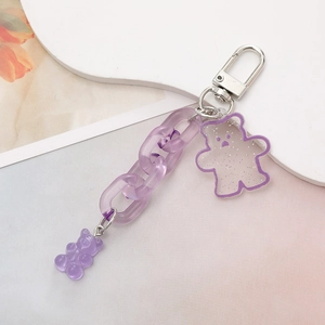 Purple acrylic bear keychain with glitter resin pendant and chunky chain on white pedestal