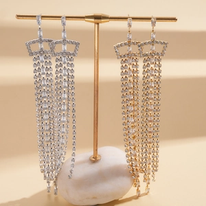 Close-up of long cubic zirconia tassel earrings in silver and gold finishes on stands