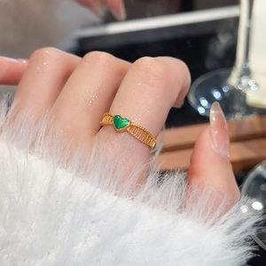 Macro shot of a 24k gold floral ring with a green heart stone and hollow lattice pattern