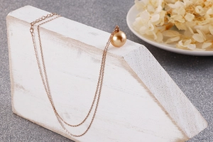 Détail d'un collier double épaisseur en acier titane rose doré avec perle dorée