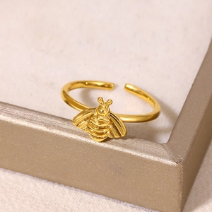 Gros plan d'une bague abeille dorée aux ailes détaillées et texture métallique polie