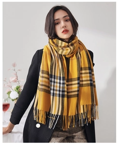 Detail shot of warm ginger yellow plaid scarf with fringe tassels and soft cashmere-like texture