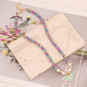 Detail of colorful clay bead necklace with mint green heart pendant and faux pearls