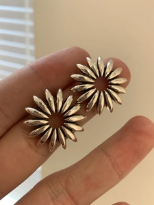 Close-up of vintage silver hollow petal earrings being held to show size and texture