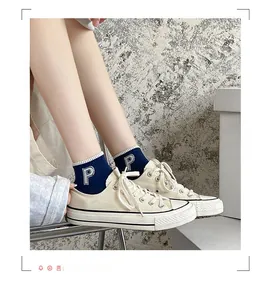 Detail of blue striped cotton socks with embroidered P letter and white canvas sneakers