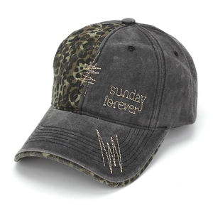 Detail view of washed denim baseball cap with green leopard patchwork and embroidery
