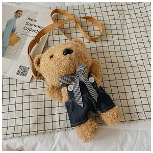 Detail of cute teddy bear plush crossbody bag in denim overalls with adjustable strap
