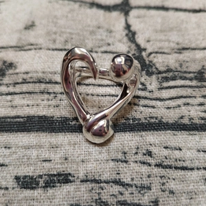Detailed top view of a silver heart-shaped nail ring with metallic sphere accents on wood